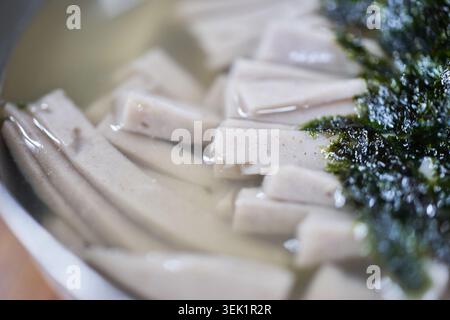 Eine Nahaufnahme des koreanischen Memilmukbap mit weichen Scheiben Buchweizengelee in einer klaren herzhaften Brühe, garniert mit gemahlenem, geröstetem Seegras. Stockfoto