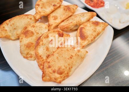 Koreanische Bratenknödel, Gunmandu, auf einem weißen Teller. Die knusprige, goldbraune Kruste fängt perfekt die herzhafte Essenz asiatischer Komfortgerichte ein. Stockfoto