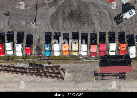 Bunte Sattelzüge parkten in einer Reihe an einem Transportdepot mit Bahngleisen in der Nähe Stockfoto