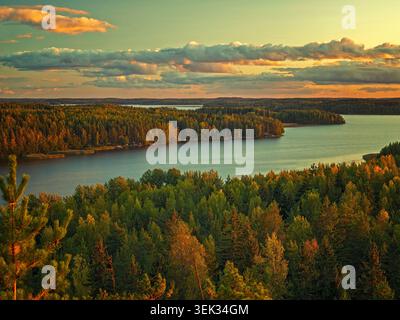 Kouvola, Finnland - 19.09.2020: Malerischer Blick auf saftig grüne und orange Baumkronen, die sich in einem ruhigen Fluss während eines pulsierenden Sonnenuntergangs spiegeln Stockfoto