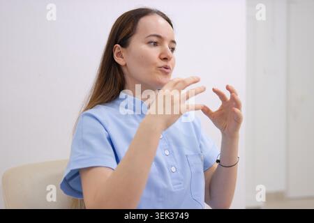 Junge Ärztin oder Krankenschwester/Krankenschwester/Ärztin, die während einer Konsultation aktiv medizinische Informationen erklärt und professionelle medizinische Beratung anbietet, c Stockfoto