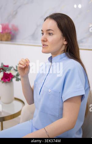 Junge weibliche Gesundheitsberaterin in hellblau schrubbt Beratung mit einem Patienten in einer Klinik, bietet aufmerksame, mitfühlende medizinische Beratung und Stockfoto