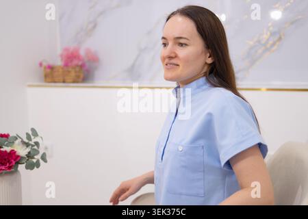 Junge Ärztin in blauer Uniform, professionell und aufmerksam in einer sauberen modernen Klinik, Vorbereitung auf die Patientenversorgung mit ruhigem Fokus und Stockfoto