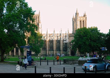 Historische gotische Türme der Kathedrale von Bristol mit einem Brunnen und Menschen, die sich auf dem grünen Rasen am College Green Square in Bristol, England, entspannen. Stockfoto