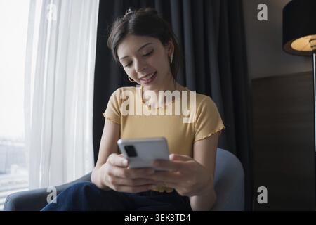 Die junge hispanische Frau der Generation Z nutzt Smartphone im modernen Technologiekonzept Stockfoto