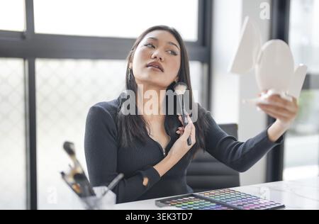 Asiatischer Make-up Künstler professioneller Blogger Vlogger zeigt kosmetische Produkte mit Aufnahme Video Beauty Influencer Asian Girl Video Online Marketing Stockfoto