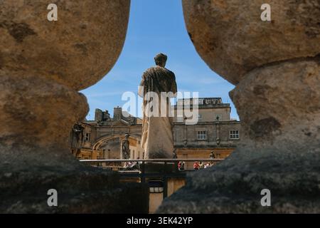 Römische Statue durch Steinbalustraden auf der Terrasse mit Blick auf das große Bad in den römischen Bädern in Bath, Somerset, Großbritannien Stockfoto