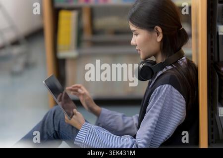 Junge asiatische Studentin, die an der Universität auf Tablet studiert Stockfoto
