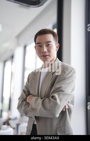 Lächelnder junger asiatischer Geschäftsmann im modernen Büro. Gutaussehender asiatischer Mann, glücklich und freundlich bei der Arbeit, Erfolg, Job Stockfoto