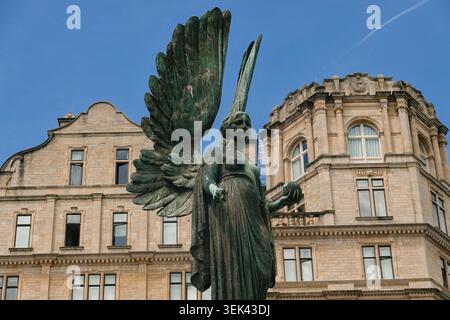 Nahaufnahme der bronzenen Engelsstatue in Parade Gardens mit der historischen Architektur des Empire Hotels in Bath, Somerset, Großbritannien Stockfoto