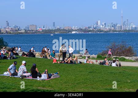 Toronto, ON, Kanada - 17. Mai 2026: Menschen genießen einen sonnigen Tag in einem Park am Lake Ontario mit der Skyline von Toronto im Hintergrund. Stockfoto