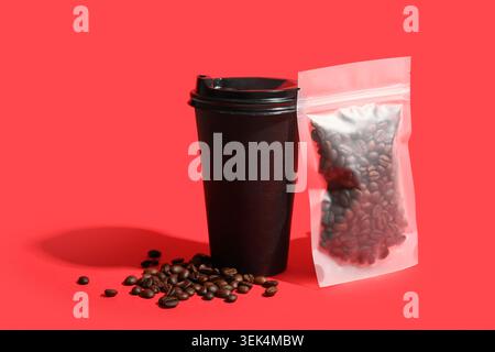 Kaffeebeutel, Pappbecher und Bohnen auf rotem Hintergrund Stockfoto