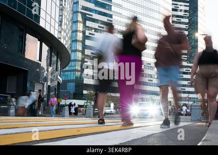 Verschwommene Menschen, die auf einem Crosswalk in einem modernen Finanzviertel mit Glashochhäusern laufen, Motion Blur City Life Konzept Stockfoto