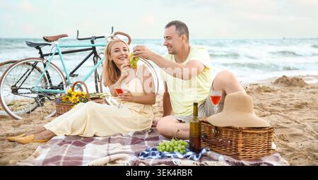 Reifes Paar, das am Sommertag in der Nähe des Meeres picknickt Stockfoto