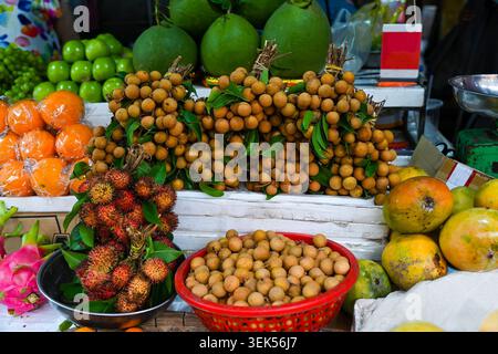 Frische tropische Früchte, einschließlich Longanzweigsträucher und reifer Rambutan, zum Verkauf auf dem traditionellen lokalen Straßenmarkt in Vietnam Stockfoto