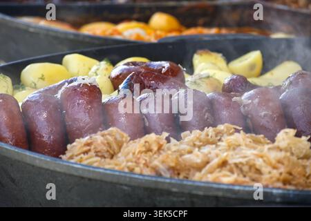 Ein Blick aus nächster Nähe auf ein traditionelles deutsches Essen mit prallen Würstchen, gekochten Kartoffeln und Sauerkraut, alles heiß serviert Stockfoto