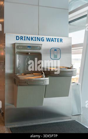 Eine saubere und moderne öffentliche Trinkwasserstation mit Edelstahlbrunnen und Nachfüllbereich für Flaschen, entworfen für eine bequeme Flüssigkeitsversorgung in einem Indoo Stockfoto