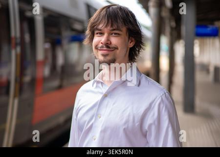 Positives Porträt eines jungen Mannes mit Bart am Bahnhof in Osterreich Stockfoto