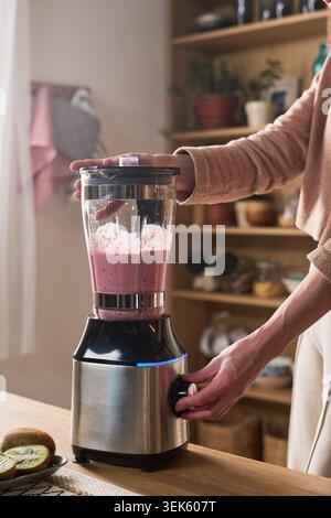 Frau mittleren Alters bereitet Smoothie für gesundes Frühstück zu Hause vor Stockfoto