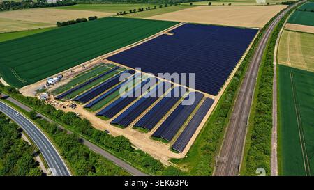 Großer Solarpark aus der Vogelperspektive umgeben von grünen und goldenen Feldern Stockfoto
