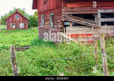 Alte rote Scheune und ein Ferienhaus in schlechtem Zustand auf dem Land Stockfoto