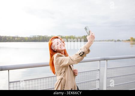 Ginger, lächelnde Frau mittleren Alters, die ein Bild von sich selbst auf einem spricht Stockfoto