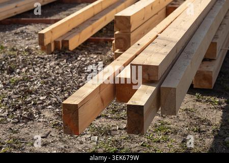 Stapel frischer Holzbalken und Holzbretter, die im Freien auf der Baustelle gelagert werden. Industrielle Tischlerei, Baustoffproduktion Stockfoto