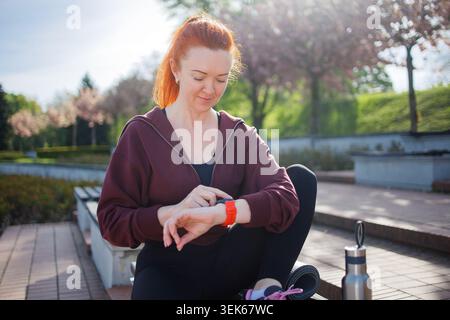 Ginger Mittelalter-Frau, die Smart Watch für die Gesundheitskontrolle während benutzt Stockfoto