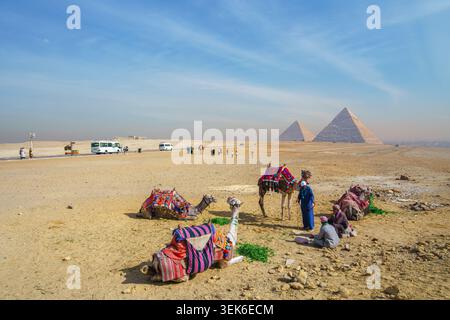 Gizeh, Ägypten - 21. Januar 2025: Beduinenmenschen ruhen mit ihren Kamelen im Wüstensand vor den historischen Pyramiden von Gizeh während einer sonnigen m Stockfoto