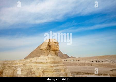 Gizeh, Ägypten - 21. Januar 2025: Seitenansicht der Großen Sphinx von Gizeh mit den alten Pyramiden im Hintergrund unter einem hellblauen Himmel in Ägypten. Stockfoto