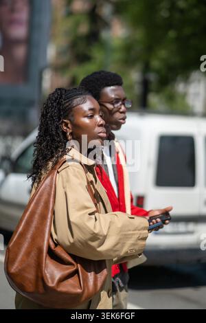 Modisches verheiratetes Paar afroamerikaner Mann und Frau stehen auf der Straße der Stadt und warten auf ein Taxi. Freundliche, stilvolle schwarze Freundinnen und Freundinnen spazieren zusammen in der Innenstadt am sonnigen Tag. Stockfoto