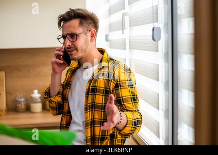 Ein besorgter junger Mann spricht zu Hause auf dem Handy. Stockfoto