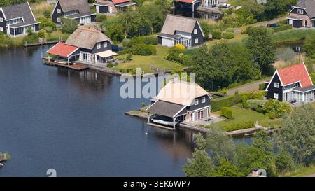 Blick aus der Vogelperspektive auf traditionelle strohgedeckte Häuser und private Bootsanleger entlang der ruhigen Kanäle, umgeben von üppigen grünen Gärten Giethoorn, Overijssel, N Stockfoto