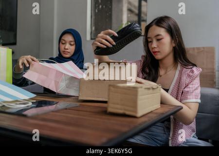 Zwei junge Frauen packen an einem Tisch in einem modernen Innenraum gelieferte Pakete aus Stockfoto