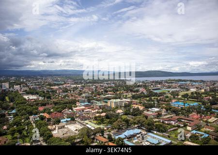 Aus der Vogelperspektive auf die weitläufige urbane Landschaft von Nakuru mit dichten Wohnhäusern und üppigen grünen Bäumen mit dem See Nakuru in der Ferne und Stockfoto