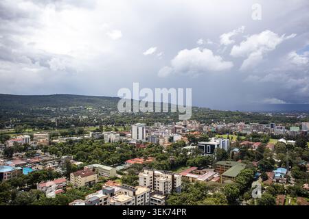 Blick aus der Vogelperspektive auf die Skyline der Stadt mit modernen Gebäuden und üppigen grünen Bäumen unter einem dramatischen bewölkten Himmel in Nakuru, Nakuru County, Kenia. Stockfoto