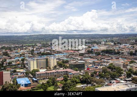 Aus der Vogelperspektive auf die Skyline der Stadt mit verschiedenen Gebäuden, grünen Bäumen und fernen Hügeln unter einem bewölkten Himmel Nakuru, Nakuru County, Kenia. Stockfoto