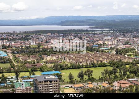 Aus der Vogelperspektive auf die urbane Landschaft von Nakuru mit Wohngebäuden, grünen Bäumen und dem See Nakuru unter hellem Himmel in Nakuru, Nakuru County Stockfoto