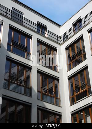 Moderne Fassade des Apartmentgebäudes mit weißen Wänden, großen Fenstern und schwarzen Balkongeländern. Städtische Wohnungs- und Wohnarchitektur Stockfoto