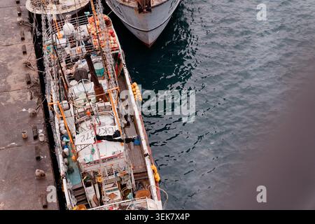 Yilan, Taiwan - 31. März 2025: Hochwinkelansicht des Schiffes in Nanfangao mit übersichtlichem Deck mit Bojen und Seilen neben dunklem Hafenwasser. Stockfoto
