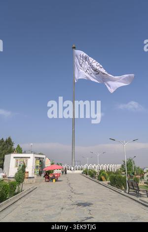 Weiße Flagge mit Shahada-Schriftzug, die von einem Fahnenmast gegen einen klaren blauen Himmel in kabul winkt Stockfoto
