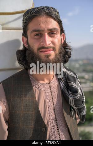 Junger Mann mit Bart und Kufi-Mütze lächelnd, in traditioneller Kleidung aus afghanistan gekleidet Stockfoto
