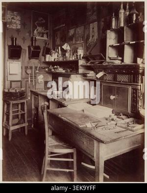 Eine Schwarzweißfotografie von Eugène Atget aus dem Jahr 1910 zeichnet das Innere eines Fotografen-Ateliers in Paris auf, dokumentiert einen Arbeitsbereich, der mit Atget verbunden ist und unter Ansichten von Wohnhäusern, vertrauten Orten und Fotostudios zu finden ist. Stockfoto