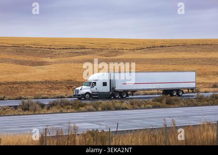 Semi-Truck, der Fracht über eine trockene Wüstenlandschaft auf einer interstate Highway transportiert Stockfoto