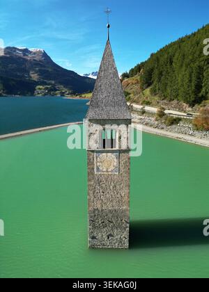 Reschensee, Südtirol, Italien – aus der Vogelperspektive auf den untergetauchten Kirchturm von Alt-Graun, der sich aus dem türkisfarbenen Reschensee mit Alpenbergen erhebt Stockfoto