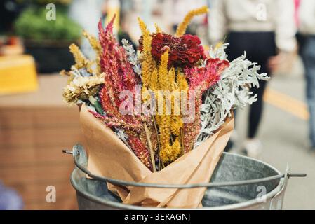 Trockene Blumen in einem rustikalen Eimer, in braunes Papier gewickelt Stockfoto