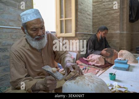 Handwerker, die an der großen Moschee mit Herat-Fliesen in einer traditionellen Werkstatt arbeiten. Stockfoto