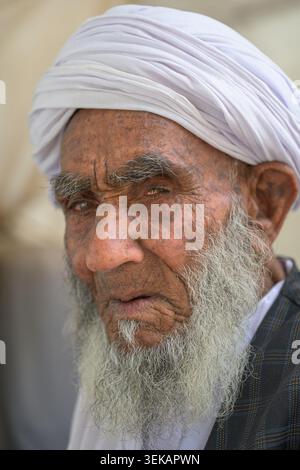 Ranghöchster afghaner mit traditionellem weißem Turban und grauem Bart, der Weisheit und Widerstandskraft in einem Nahporträt zeigt Stockfoto