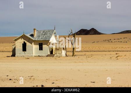 Eindringlicher Blick auf einen verlassenen Bahnhof und toten Baum in den trockenen Weiten des Sperrgebietes, Namibia Stockfoto