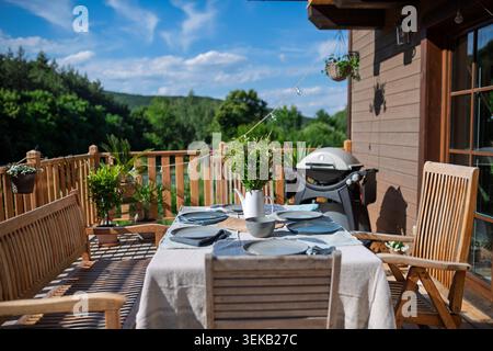 Grill im Freien auf Holzterrasse mit Esstisch und Grill. Stockfoto